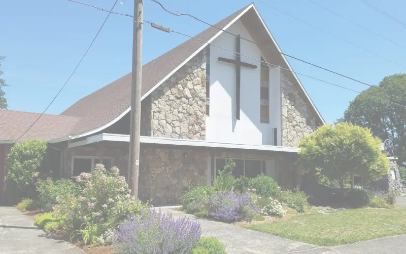 The front of Woodland Christian Church framed by summer flowers